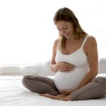 Happy,Expectant,Mother,Sitting,On,Bed,,Feeling,Kicks,,Caressing,Big