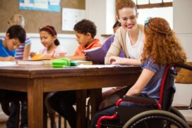 Primary school teacher helping child with special educational needs classroom UK landscape