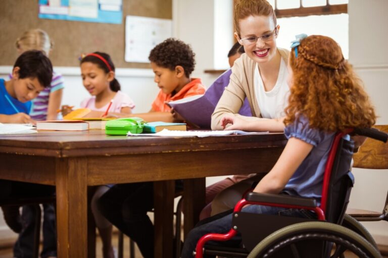 Primary school teacher helping child with special educational needs classroom UK landscape